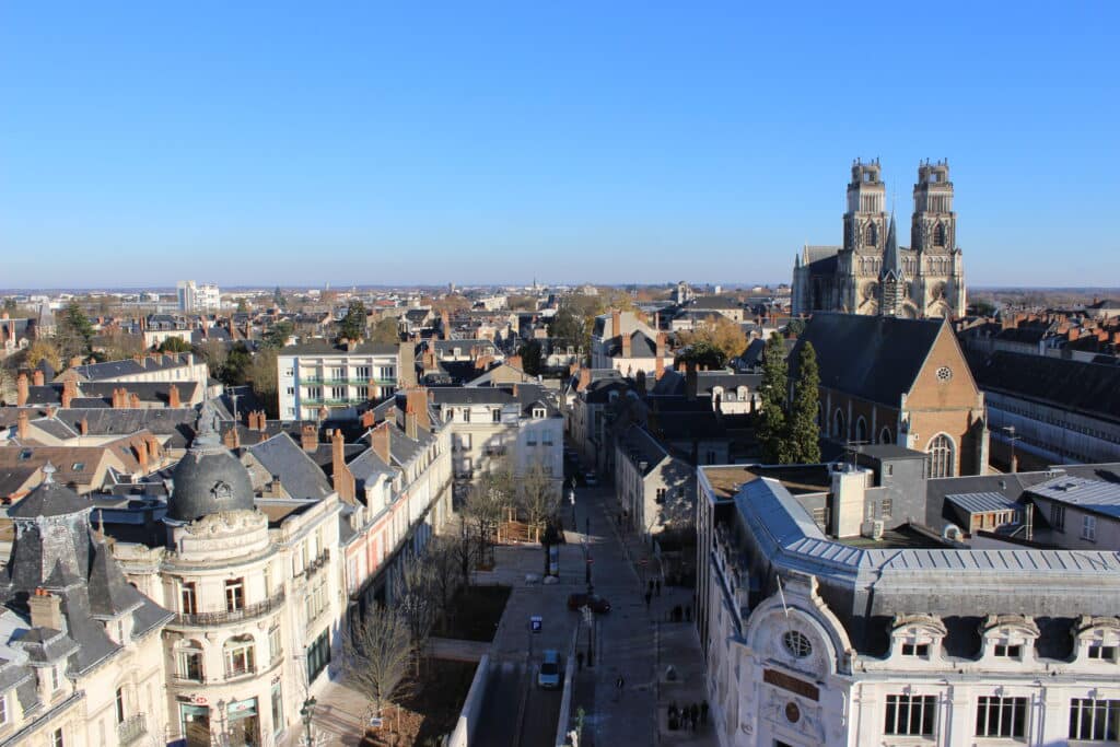 Orléans, France: Vue aérienne de la Cathédrale Sainte-Croix et ses tours. Cityscape urbain dense, toits, rues animées. Texte: BANQUE, HSBC, LYONNAIS.